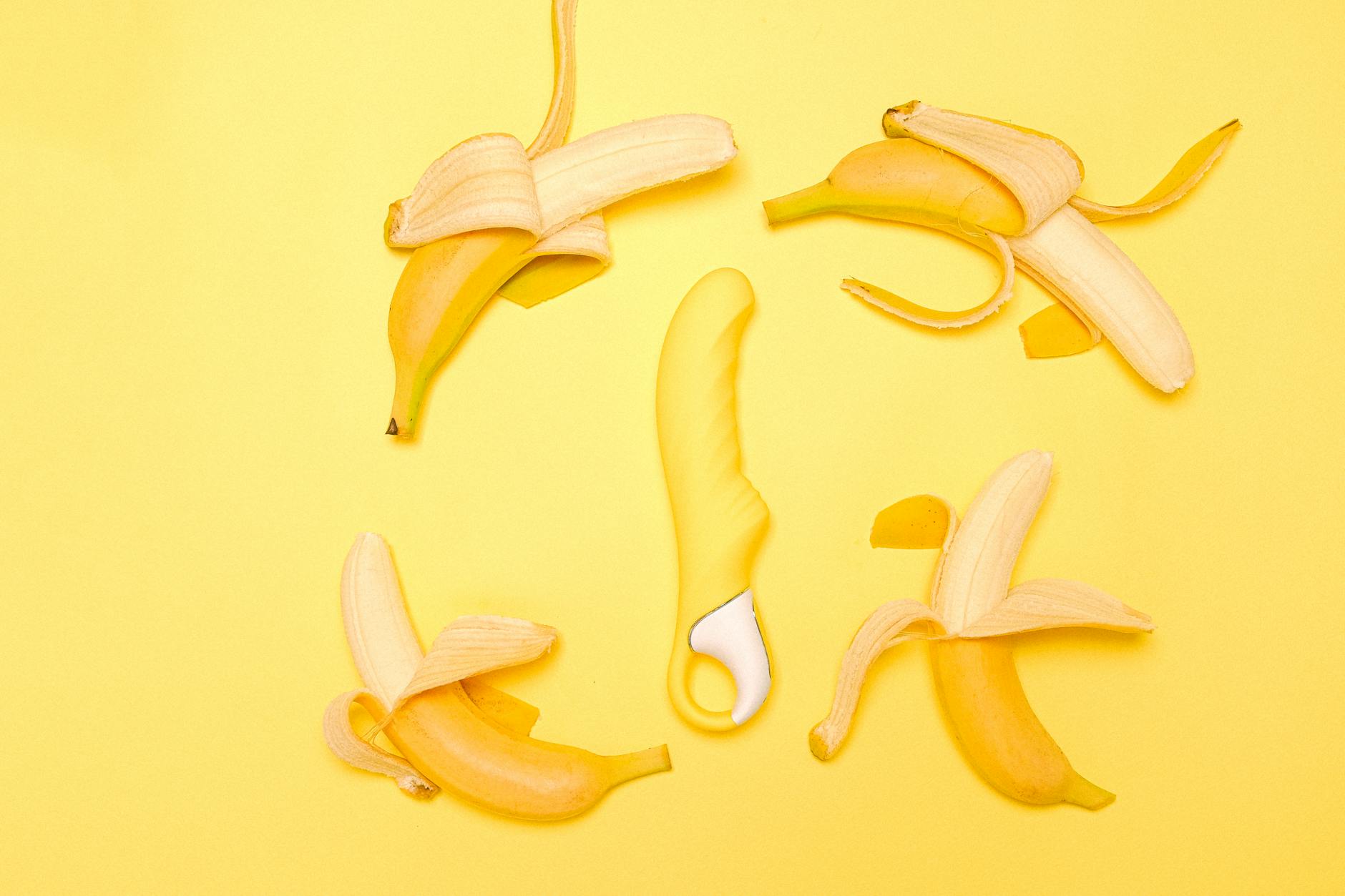 A bright yellow lemon vibrator surrounded by peeled lemons on a sunny yellow background
