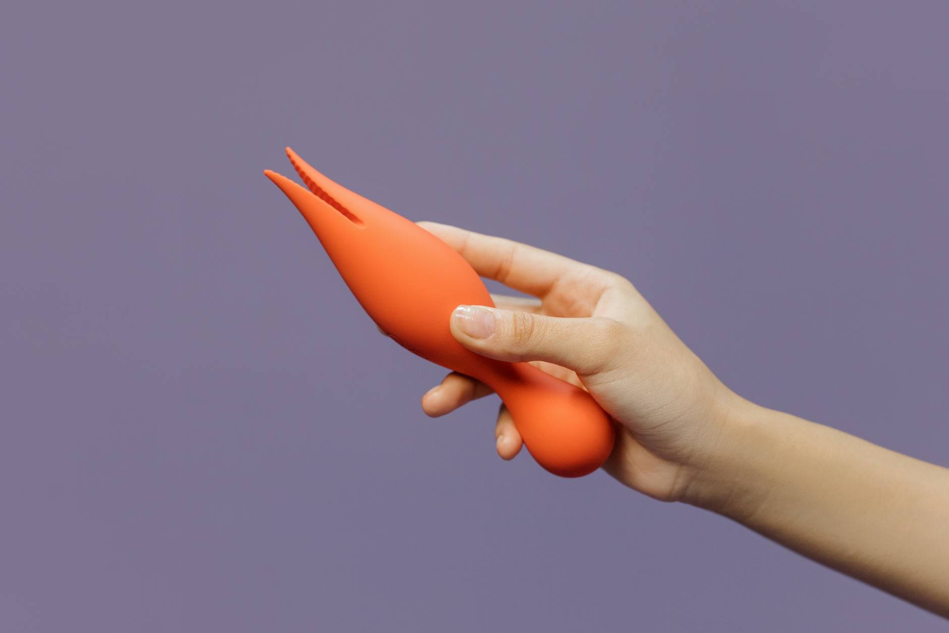 Close-up of hands holding a lemon-colored vibrator against a minimalist background