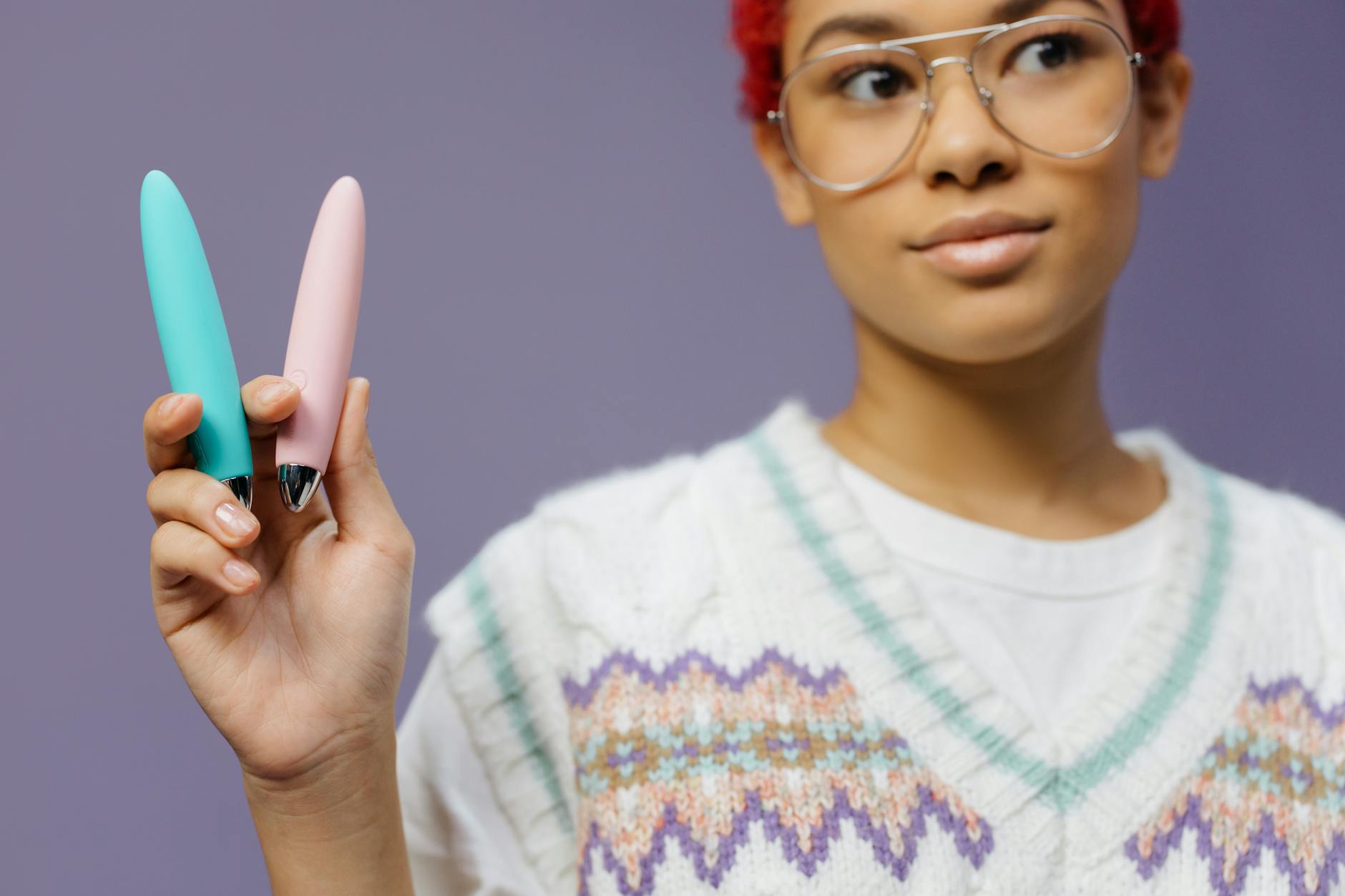 A person holding colorful vibrators against a vibrant background, representing pleasure wellness options