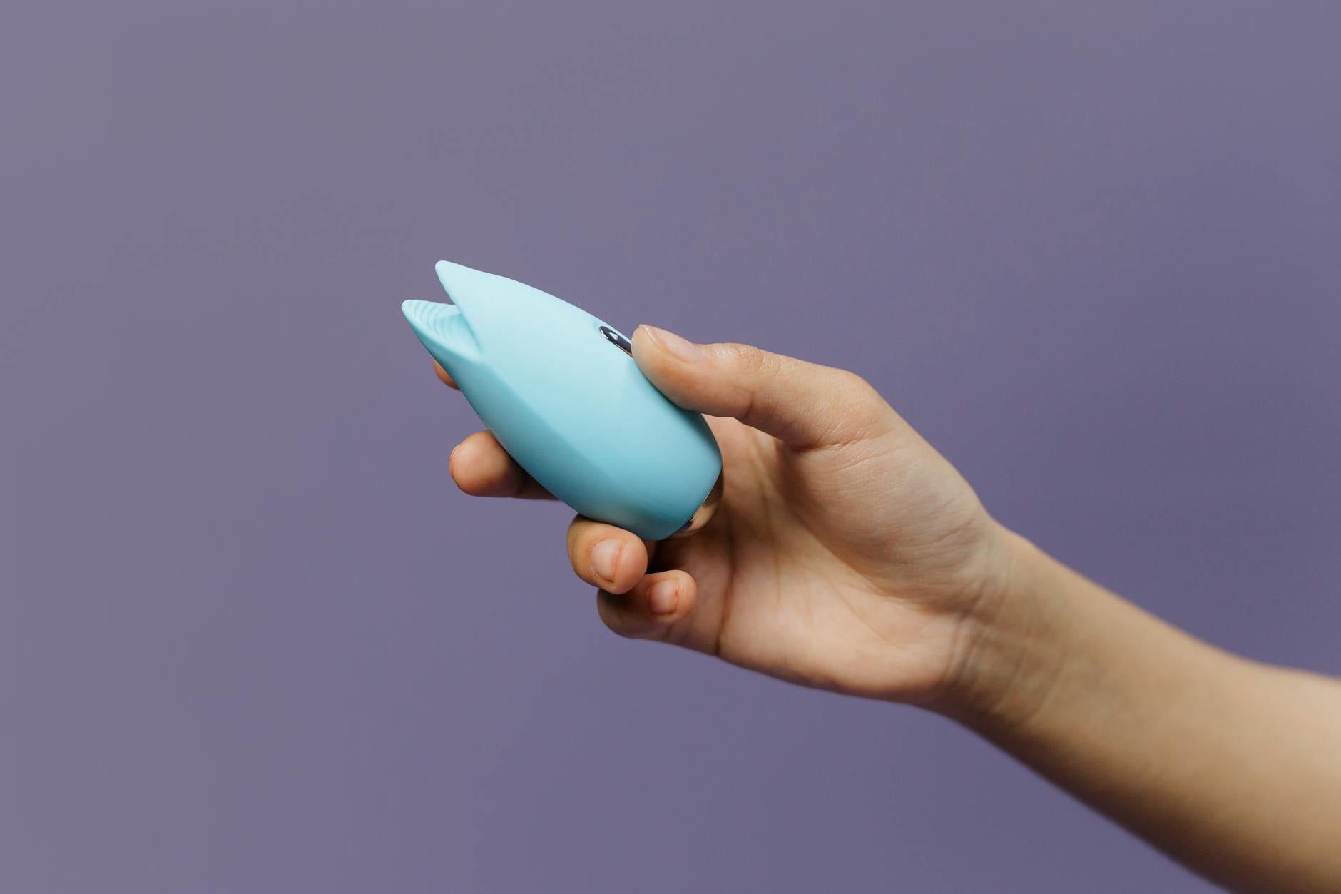 A blue silicone vibrator held in hand, representing modern pleasure tools