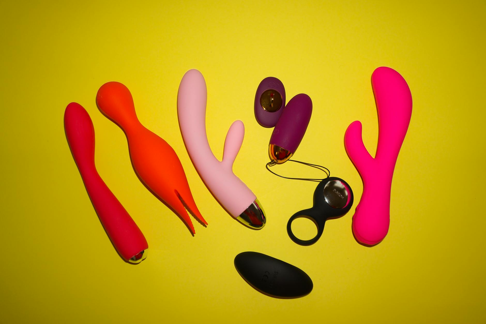 Woman holding blue and pink silicone vibrators in contemplative moment